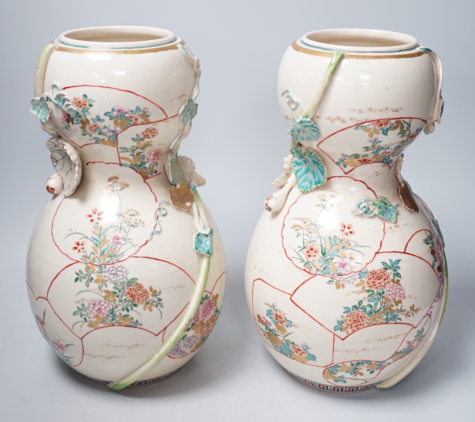 A pair of large late 19th century Satsuma pottery gourd shaped vases, each modelled with a gourd vine, 33cm tall